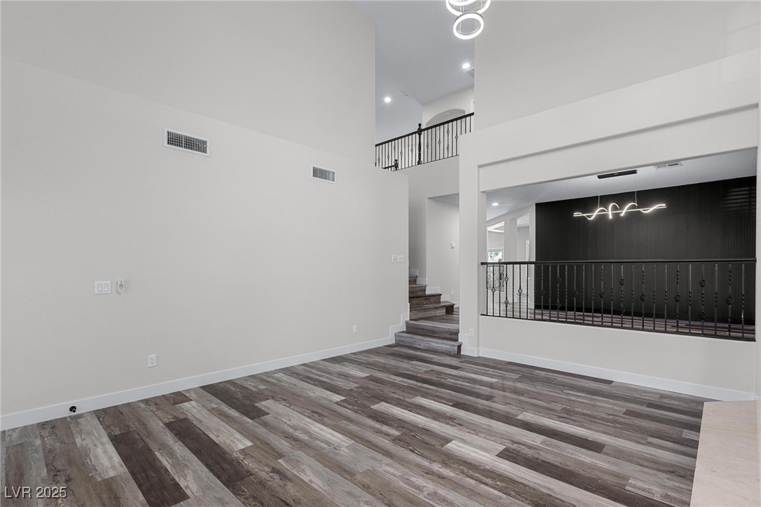9591 Antelope Bend Court Las Vegas, NV 89148 - Photo 8 of 56 Unfurnished living room with a chandelier, a high ceiling, a fireplace, and dark wood-style floors