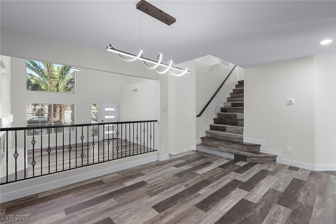 9591 Antelope Bend Court Las Vegas, NV 89148 - Photo 10 of 56 Unfurnished dining room featuring dark wood finished floors, a chandelier, and an accent wall overlooking the living room