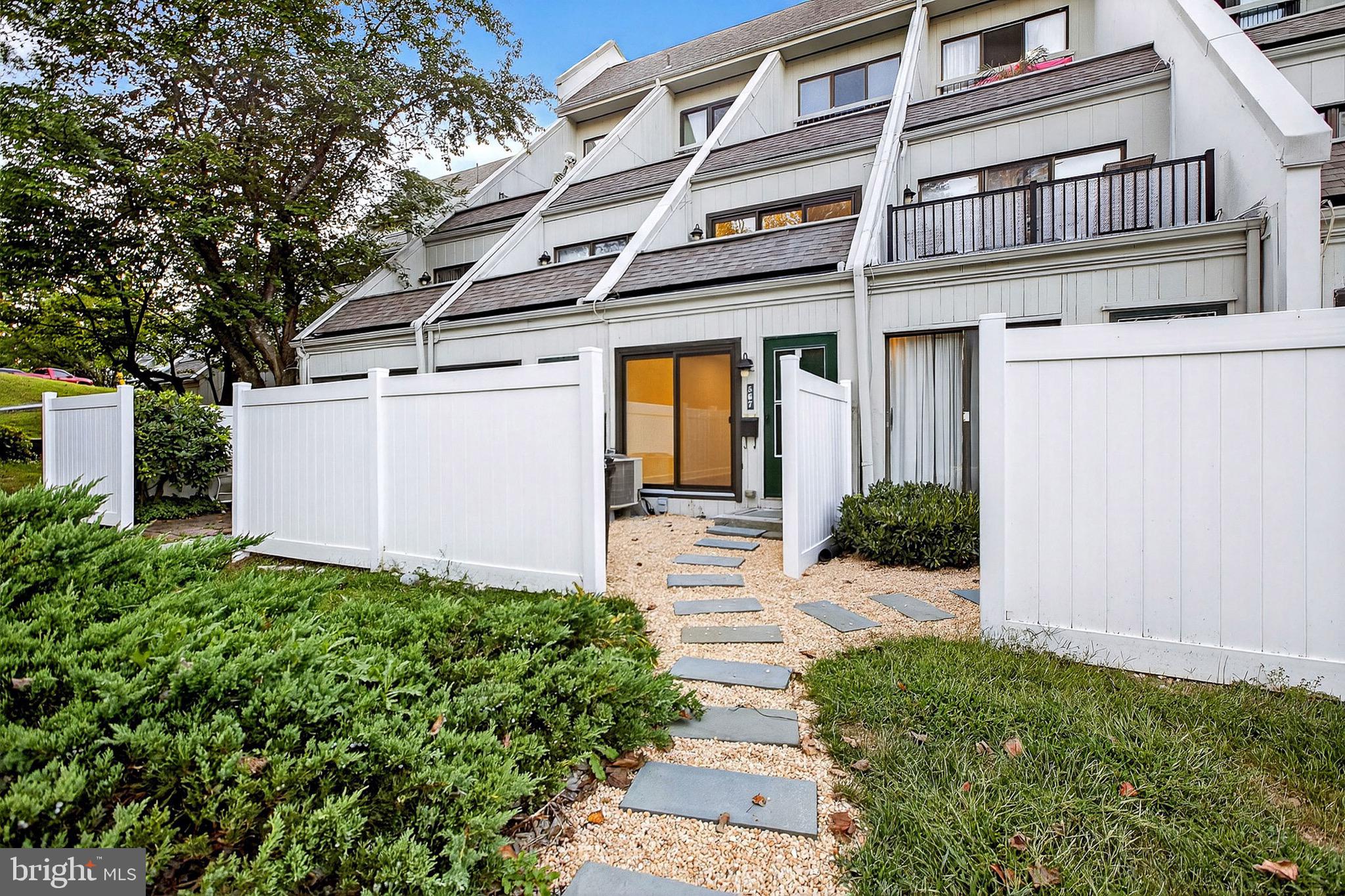 a view of a house with a small yard plants and large tree