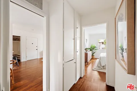 a view of a hallway with wooden floor and a bedroom