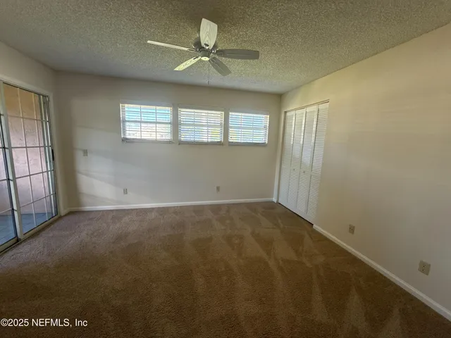 an empty room with windows and fan