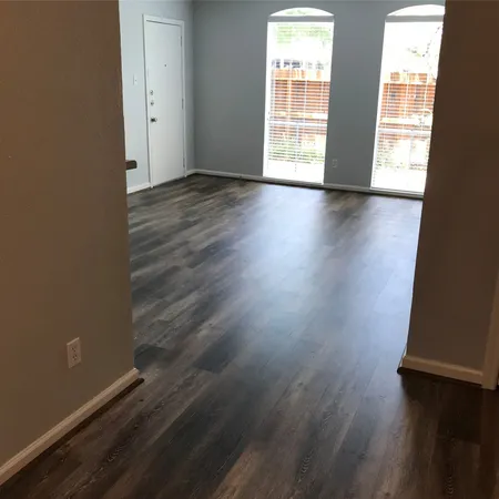 an empty room with wooden floor and windows with curtains