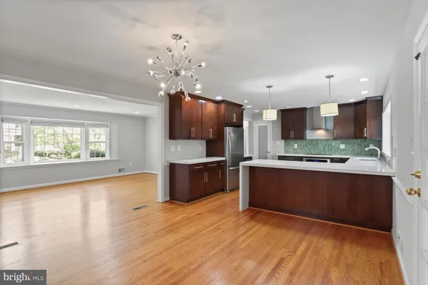 a large kitchen with stainless steel appliances granite countertop a large counter top a sink dishwasher and a stove with wooden floor