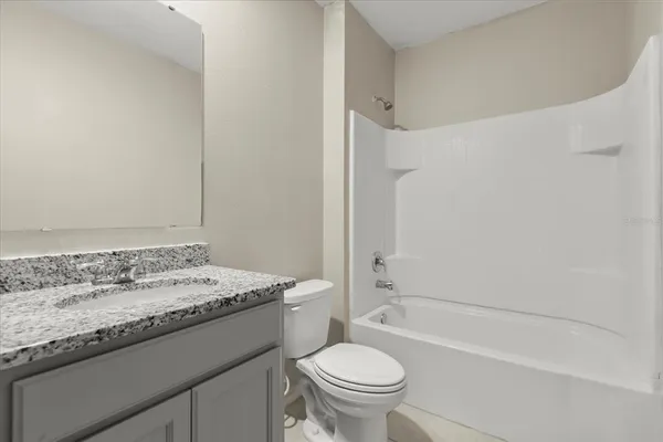 a bathroom with a granite countertop sink a toilet and shower