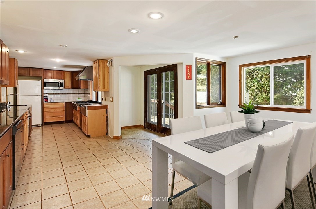 1000 Duchess Road Bothell, WA 98012 - Photo 11 of 35 a kitchen with stainless steel appliances granite countertop a stove a sink dishwasher a dining table and chairs with wooden floor