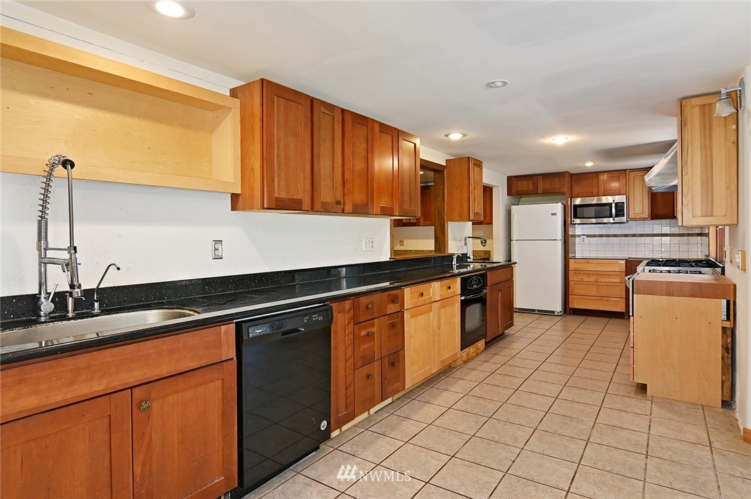 1000 Duchess Road Bothell, WA 98012 - Photo 13 of 35 a kitchen with stainless steel appliances granite countertop a sink counter space cabinets and a large window