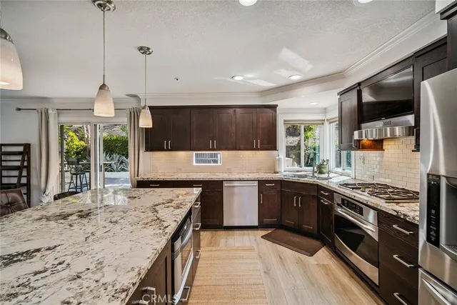 a kitchen with stainless steel appliances granite countertop wooden cabinets a stove a sink and a wooden floors