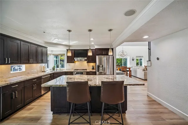 a kitchen with stainless steel appliances kitchen island granite countertop a table chairs sink and cabinets