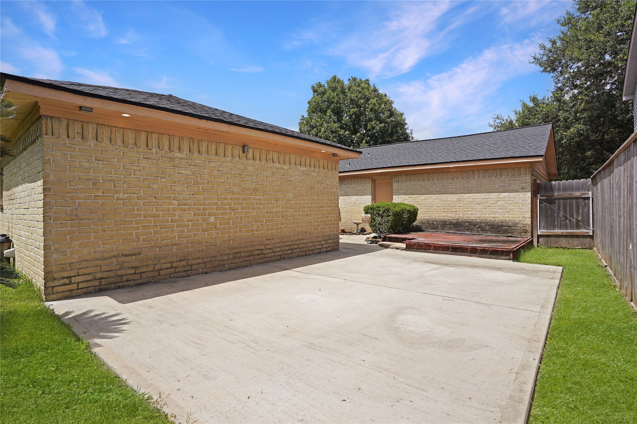 17119 Mellow Ridge Drive Spring, TX 77379 - Photo 29 of 32 This photo showcases a spacious, fenced backyard with a concrete patio area, ideal for outdoor activities. The brick exterior buildings offer a durable and low-maintenance aesthetic, surrounded by a small lawn and greenery, perfect for relaxation or entertaining.