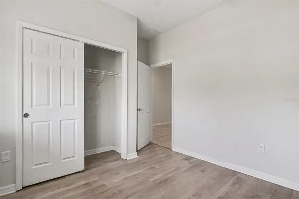 an empty room with wooden floor & closet area