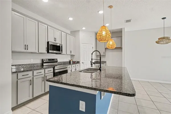 a kitchen with kitchen island granite countertop a sink a stove cabinets and a counter top space