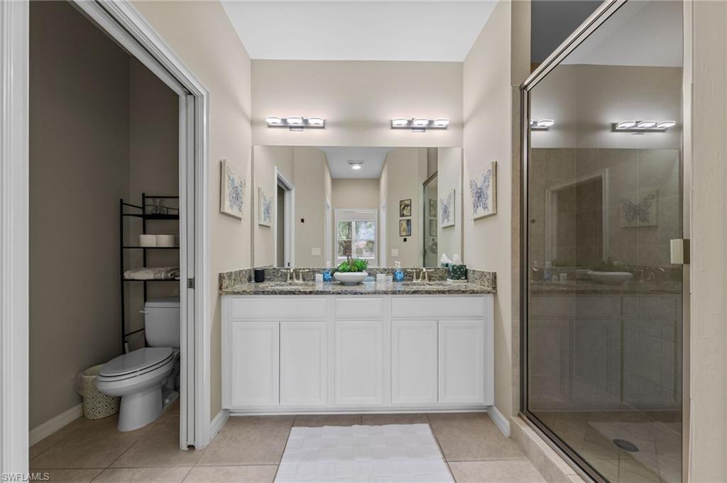 9366 Pocida Court, Unit 202 Naples, FL 34119 - Photo 18 of 44 a bathroom with a granite countertop sink a toilet a mirror and shower