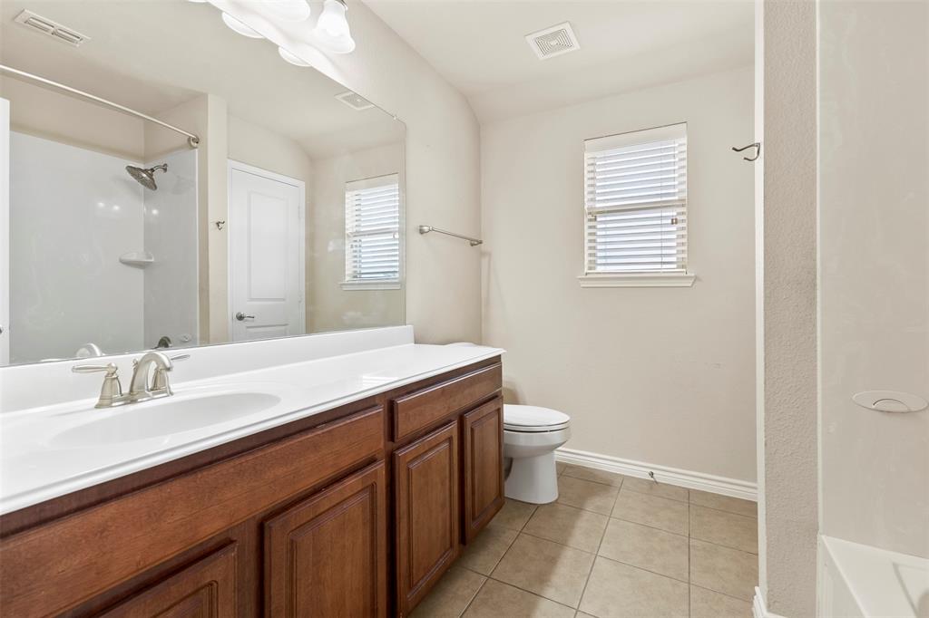 6522 Portside Ridge Lane Dallas, TX 75249 - Photo 23 of 37 Bathroom featuring a dual-sink vanity with wood-finish cabinetry, a white countertop, and brushed nickel fixtures