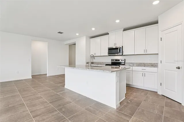 a kitchen with kitchen island granite countertop a stove top oven a sink a counter top space and cabinets