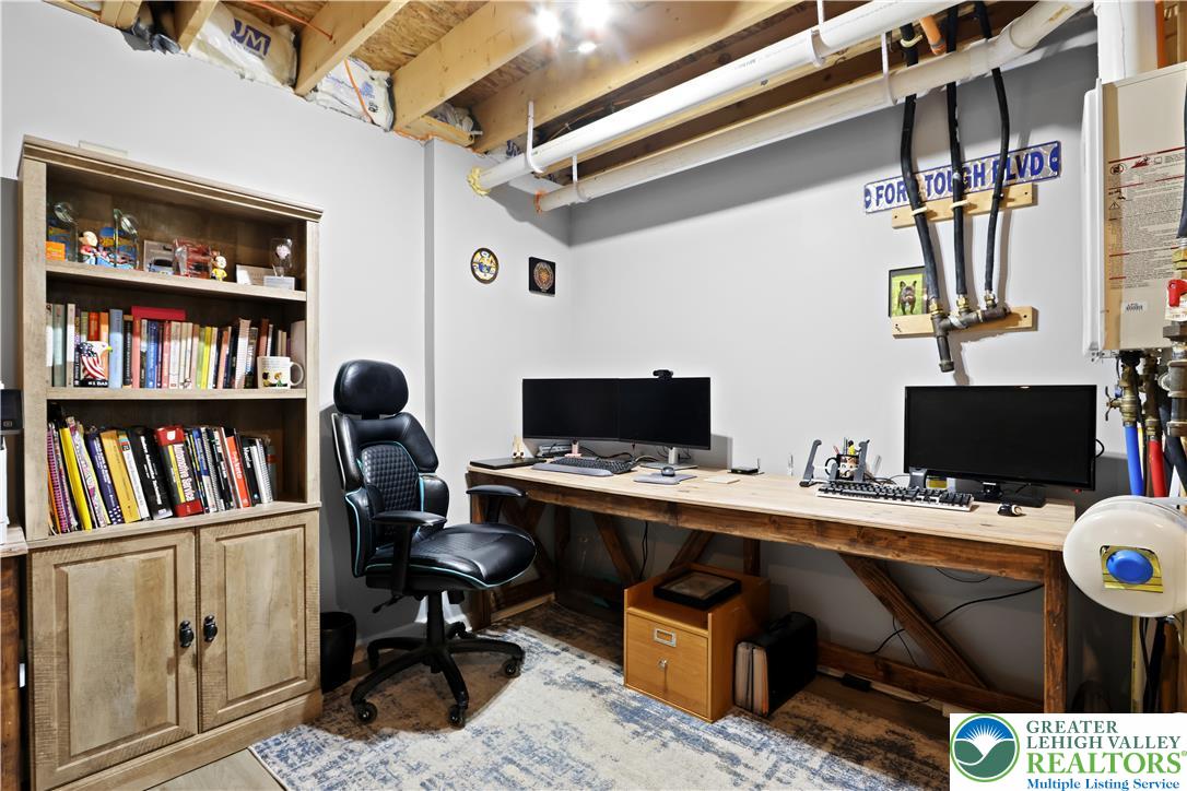 2336 Alex Road Easton, PA 18040 - Photo 22 of 35 A dedicated home office space with built-in shelving, an expansive desk, and exposed ceiling beams.