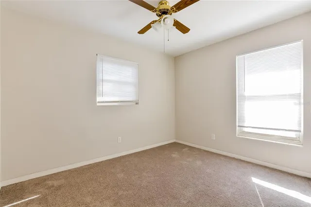 an empty room with a window and a fan