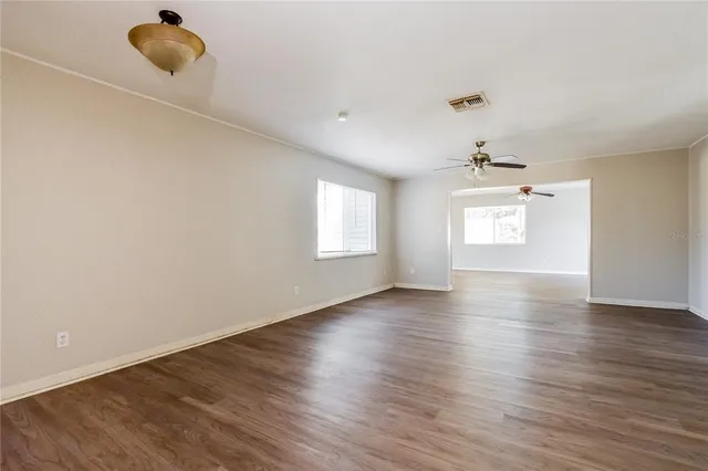 a view of an empty room and window and wooden floor