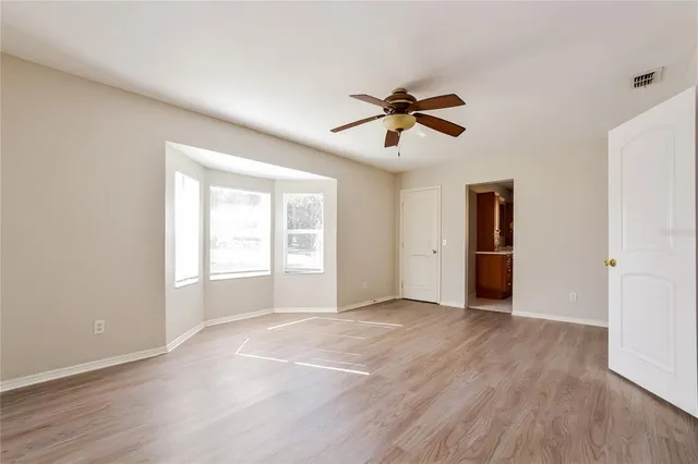 a view of empty room with wooden floor and ceiling fan