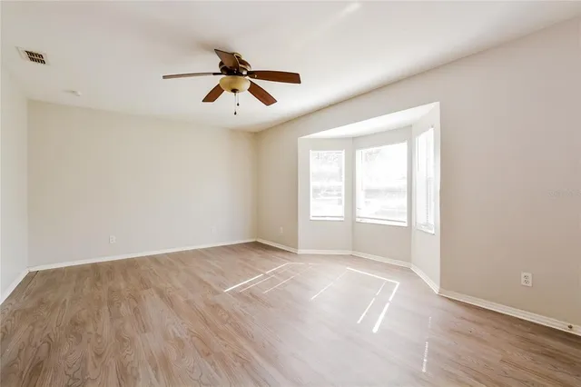 a view of empty room with wooden floor and fan