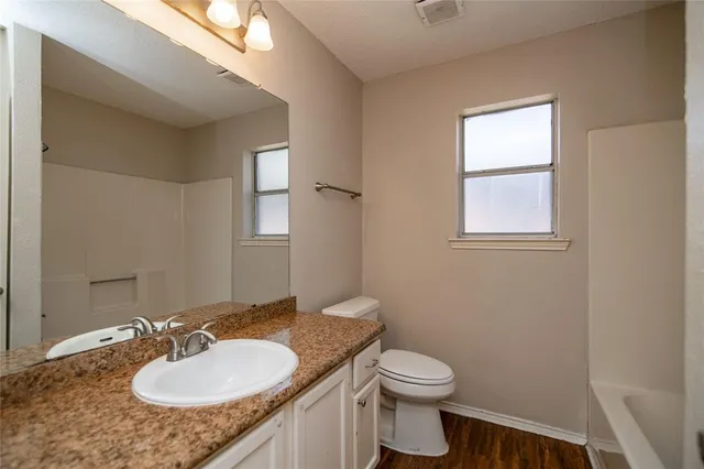 a bathroom with a granite countertop sink toilet and mirror