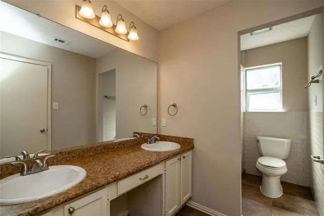 a bathroom with a granite countertop sink a toilet and a mirror