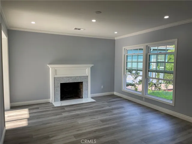 an empty room with wooden floor fireplace and windows