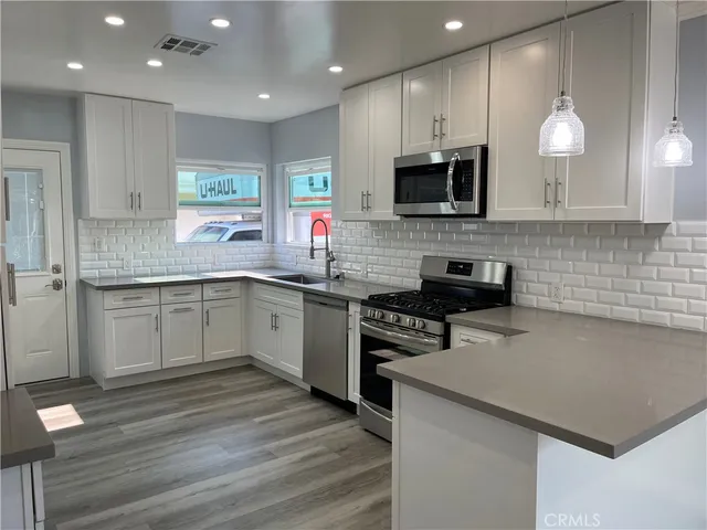 a kitchen with stainless steel appliances granite countertop a sink a stove top oven a counter space and cabinets