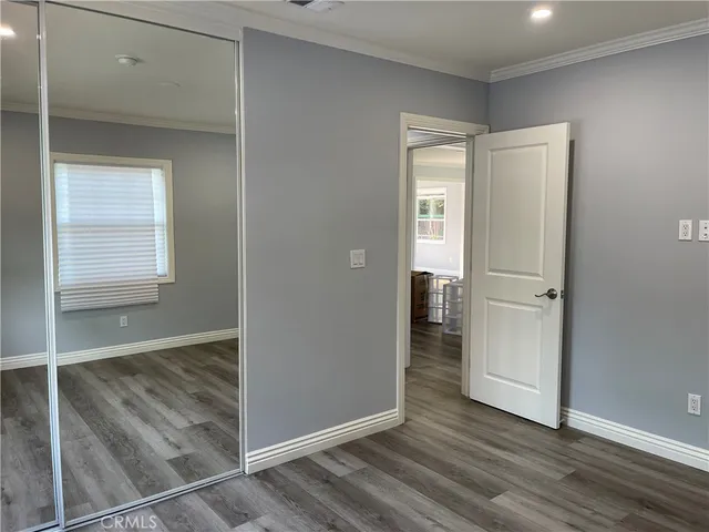 an empty room with wooden floor cabinet and windows