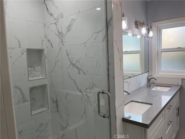 a bathroom with a double vanity sink mirror and shower