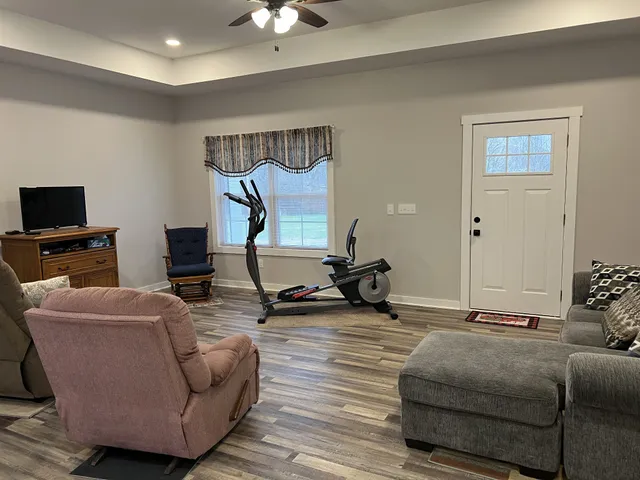 a living room with furniture a flat screen tv and a ceiling fan