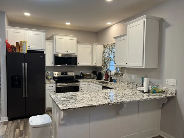 a kitchen with stainless steel appliances granite countertop a sink refrigerator and microwave