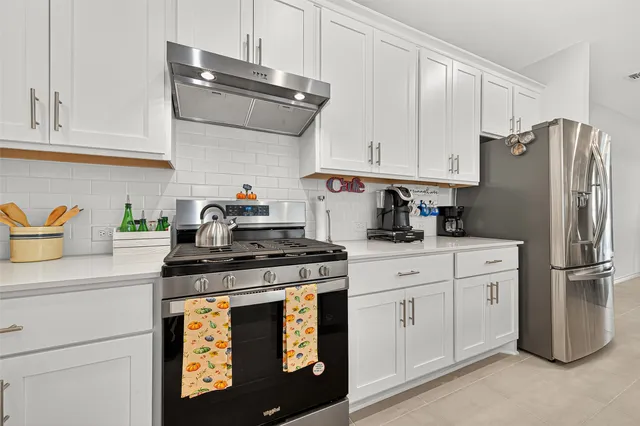 a kitchen with stainless steel appliances granite countertop a refrigerator sink and white cabinets
