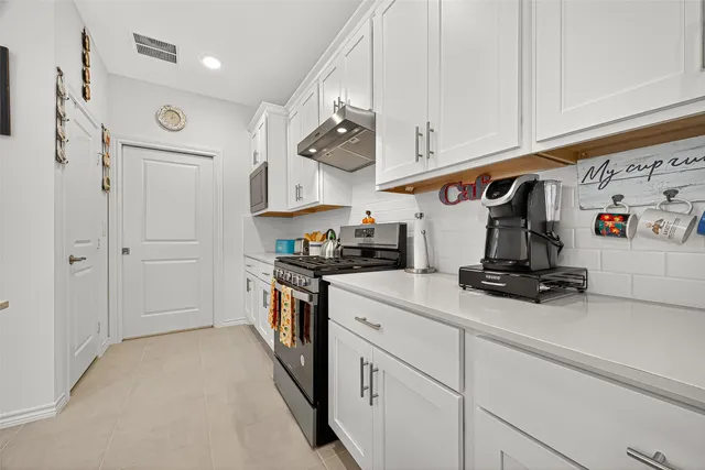 a kitchen with stainless steel appliances granite countertop a refrigerator a stove and white cabinets