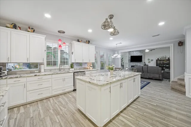 a room with kitchen island granite countertop lots of counter top space and sink