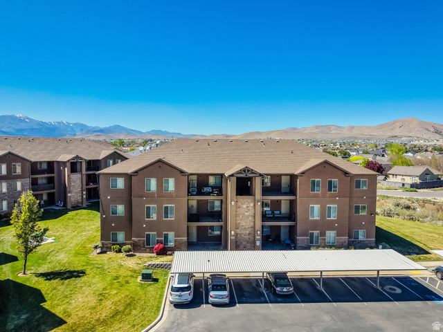 8215 Clear Rock Road, Unit 12 Eagle Mountain, UT 84005 - Photo 17 of 38 Multistory residential building with a brown stucco and stone facade, private balconies, and a covered parking structure