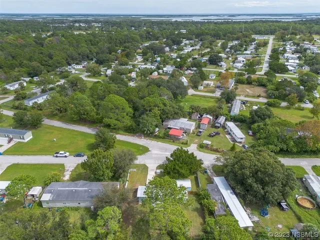 an aerial view of residential houses with outdoor space and trees
