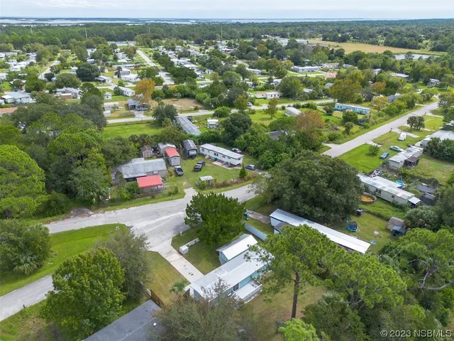 an aerial view of residential houses with outdoor space and trees