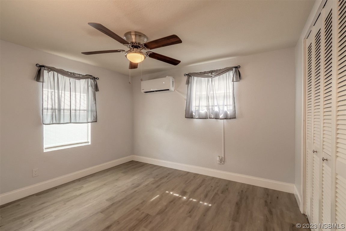 153 West Loop Oak Hill, FL 32759 - Photo 6 of 32 an empty room with wooden floor fan and windows