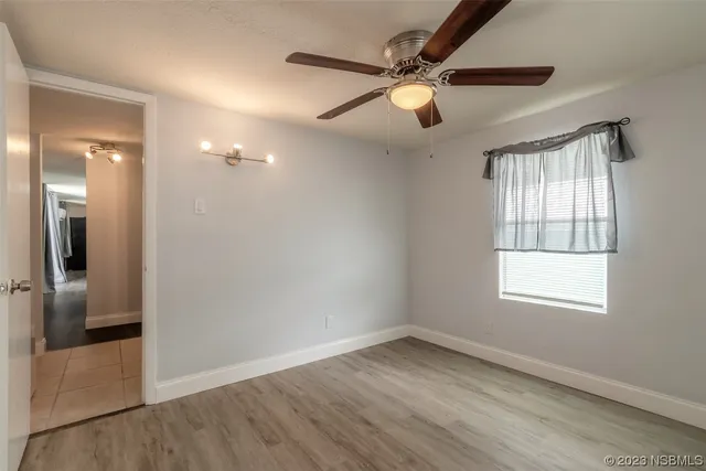 an empty room with wooden floor fan and windows
