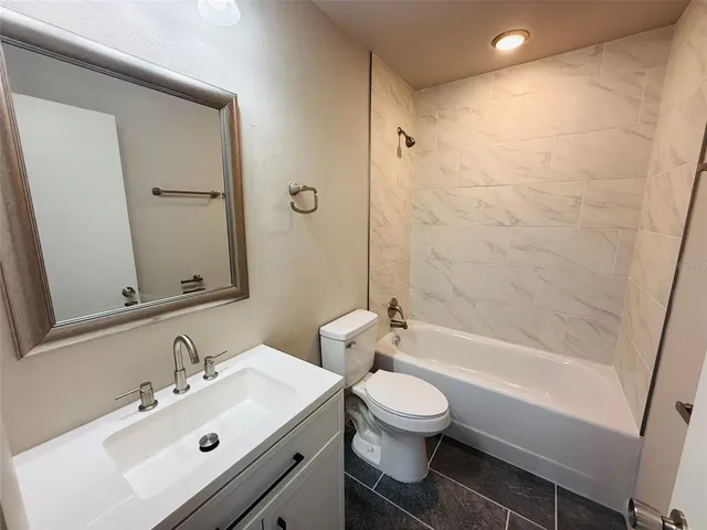 a bathroom with a bathtub shower sink vanity mirror and toilet