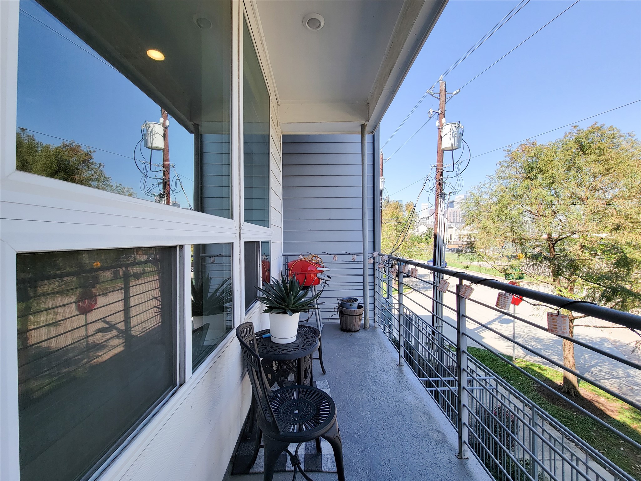 1705 Eado Point Lane Houston, TX 77003 - Photo 34 of 50 A cozy balcony with a seating area. The balcony is enclosed by a modern metal railing and offers a view of the street and surrounding greenery. Large windows provide ample natural light to the adjacent interior space.