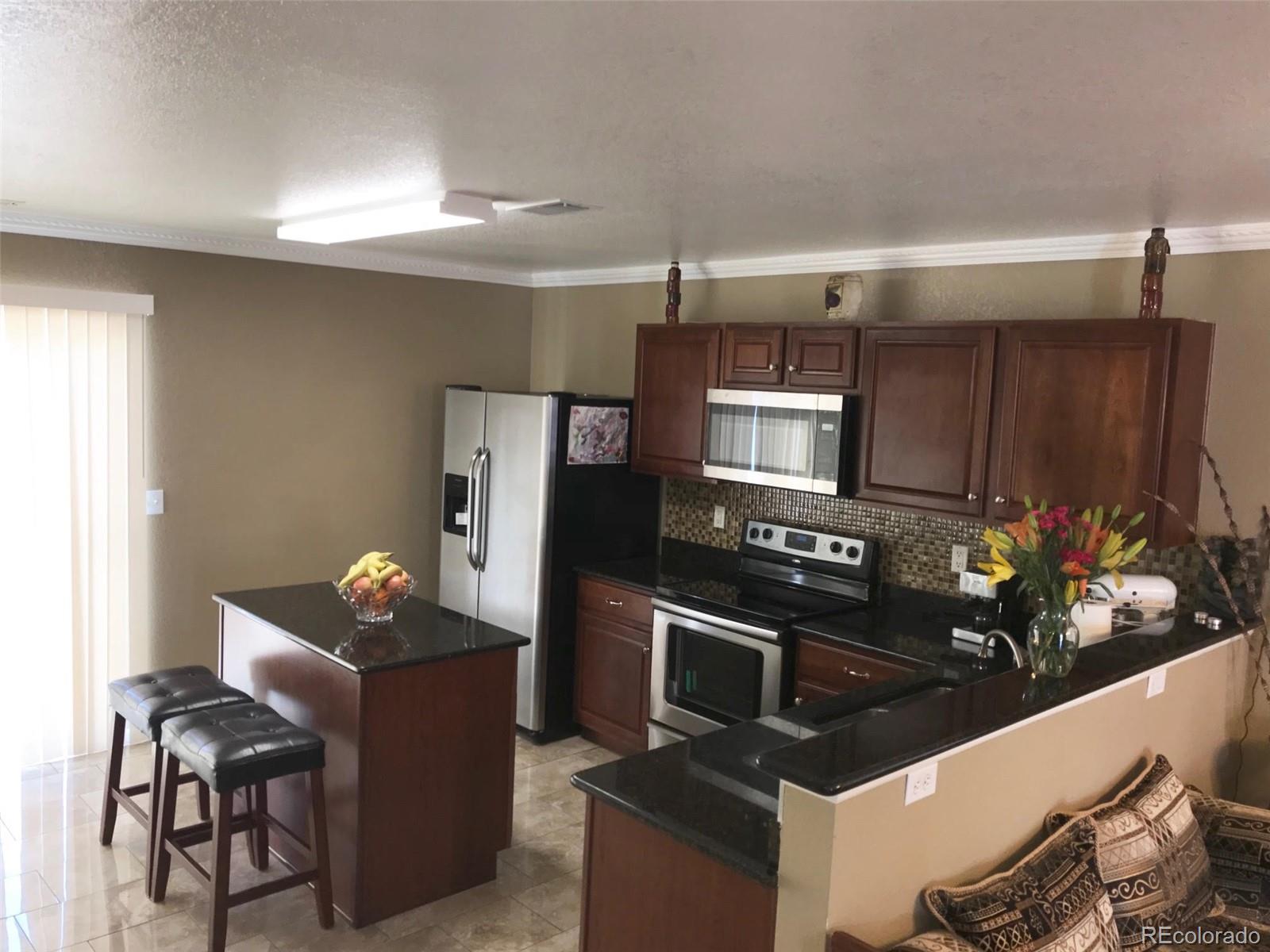 5556 Flanders Way Denver, CO 80249 - Photo 13 of 23 a kitchen with granite countertop a stove and refrigerator