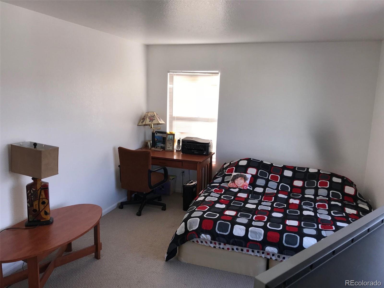 5556 Flanders Way Denver, CO 80249 - Photo 16 of 23 a bedroom with a bed and a chair