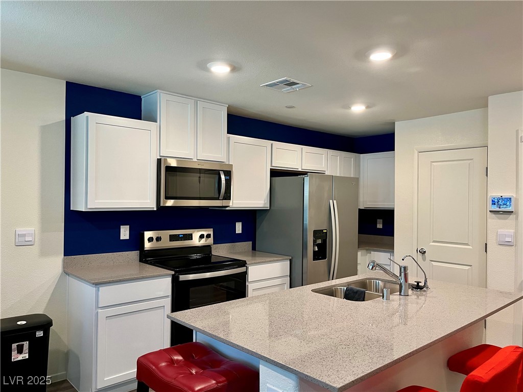 4862 Orchid Rdg Avenue Las Vegas, NV 89141 - Photo 11 of 48 Kitchen w/island w/breakfast bar, quartz countertops, white shaker cabinets, stainless steel Whirlpool appliances including refrigerator, microwave, dishwasher, stove, reverse osmosis, recessed lights, luxury vinyl plank floors & pantry.