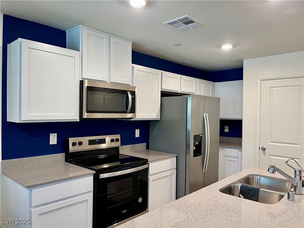 4862 Orchid Rdg Avenue Las Vegas, NV 89141 - Photo 12 of 48 Kitchen w/island w/breakfast bar, quartz countertops, white shaker cabinets, stainless steel Whirlpool appliances including refrigerator, microwave, dishwasher, stove, reverse osmosis, recessed lights, luxury vinyl plank floors & pantry.