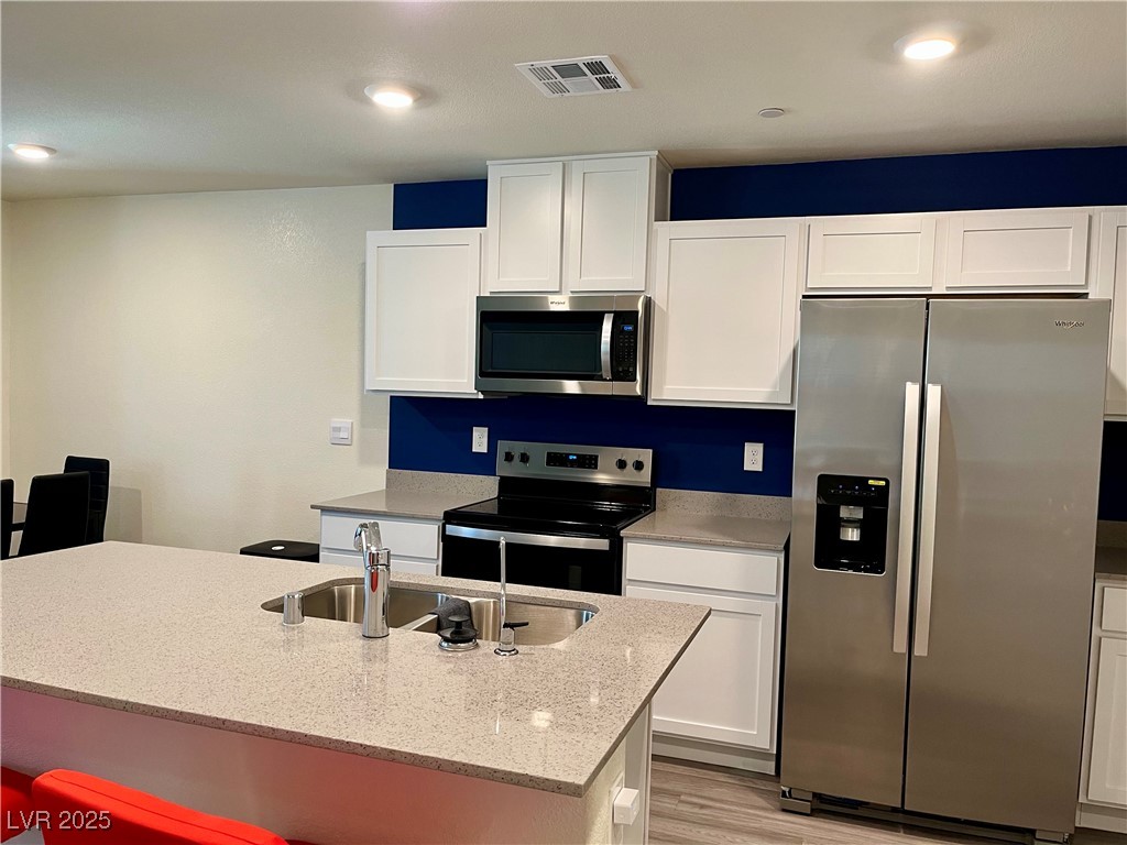 4862 Orchid Rdg Avenue Las Vegas, NV 89141 - Photo 14 of 48 Kitchen w/island w/breakfast bar, quartz countertops, white shaker cabinets, stainless steel Whirlpool appliances including refrigerator, microwave, dishwasher, stove, reverse osmosis, recessed lights, luxury vinyl plank floors & pantry.