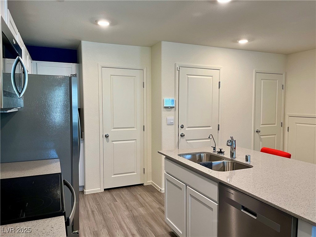 4862 Orchid Rdg Avenue Las Vegas, NV 89141 - Photo 16 of 48 Kitchen w/island w/breakfast bar, quartz countertops, white shaker cabinets, stainless steel Whirlpool appliances including refrigerator, microwave, dishwasher, stove, reverse osmosis, recessed lights, luxury vinyl plank floors & pantry.