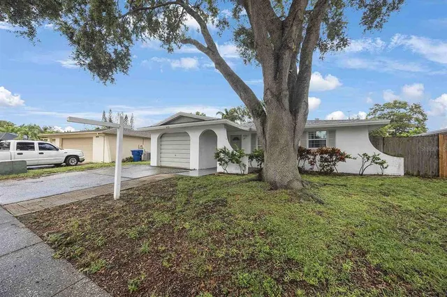 a view of a white house with a yard and large tree