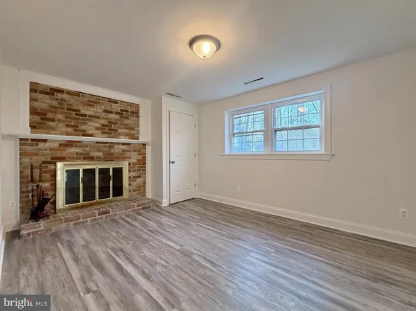 an empty room with wooden floor fireplace and windows