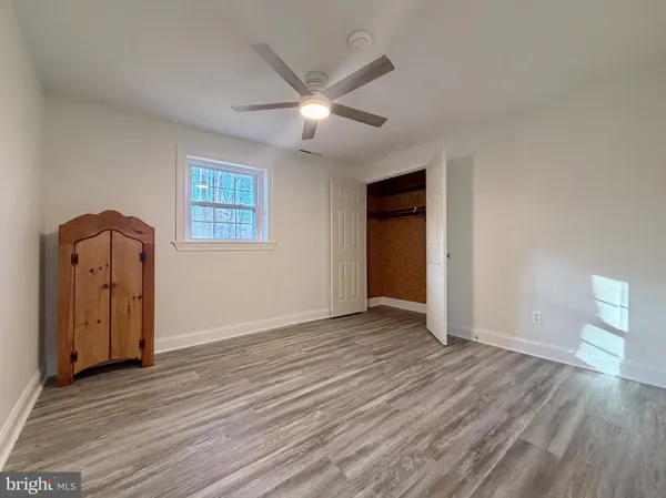 an empty room with wooden floor and a ceiling fan